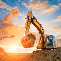 Zwei Bagger arbeiten im frühen Morgenlicht auf einer Baustelle