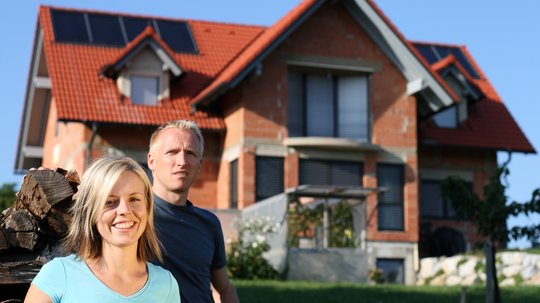 Paar vor einem neu gebauten Einfamilienhaus