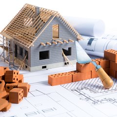 Ein Bauplan mit Modellhaus und Maurerkelle